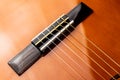 Detail of the wooden bridge of a Spanish or classical guitar with brown and orange color Royalty Free Stock Photo