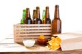 Photo of different full beer bottles with no labels and paper pack of potato chips on table, souces Royalty Free Stock Photo