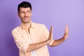 Photo of disgusted young man hands show refusal gesture empty space wear beige shirt purple color background