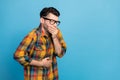 Photo of displeased unsatisfied man in glasses dressed plaid shirt feel bad arm cover mouth stomach isolated on blue Royalty Free Stock Photo