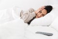 Photo of displeased woman 30s grabbing head due to smartphone, while lying in bed with white linen at home Royalty Free Stock Photo