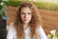 Photo of dissatisfied curly female model frowns face, feels tired and annoyed as waits for someone for long time in cafe, doesn`t