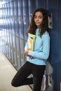 Diverse Junior High school Student standing by her locker in a school hallway
