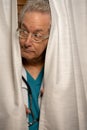 Photo of a doctor hiding in his office behind the curtains