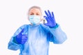 The photo of a doctor in medical uniform, protective face mask and gloves holding in one hand vaccine bottle against