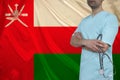 Photo of a doctor with a stethoscope on the background of the Oman national flag on a beautiful silk fabric, the concept of