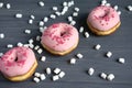 Photo with donuts and marshmallows on a black wooden background. Sweets on a dark background. Pink donuts
