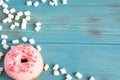 Photo with donuts and marshmallows on a blue wooden background. Sweets on a color background. Pink donuts