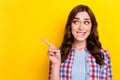 Photo of doubtful uncertain lady wear plaid shirt looking pointing finger empty space isolated yellow color background