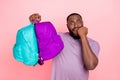 Photo of doubtful unsure guy dressed violet t-shirt biting hand rising two rucksacks isolated pink color background Royalty Free Stock Photo