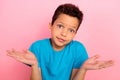 Photo of doubtful unsure small boy wear blue t-shirt shrugging shoulders isolated pink color background Royalty Free Stock Photo