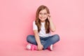 Photo of dream funny little girl sit floor wear glasses white t-shirt jeans shoes  pink color background Royalty Free Stock Photo