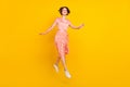Photo of dream girl jump enjoy flight step wear striped dress sneakers yellow color background