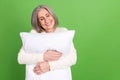 Photo of dreaming closed eyes relax comfort chilling glad woman pensioner embrace pillow smiling isolated on green color