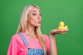 Photo of dreamy affectionate lady hold duck rubber toy send air kiss wear striped overall isolated green color