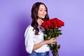 Photo of dreamy affectionate lady smell roses close eyes wear white shirt isolated purple color background Royalty Free Stock Photo