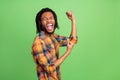 Photo of dreamy astonished dark skin guy dressed checkered shirt rising fists smiling green color background