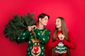 Photo of dreamy couple guy hold x-mas tree girl look hopeful wear ugly pullover isolated red color background Royalty Free Stock Photo