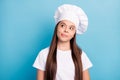 Photo of dreamy happy little girl cook look empty space lick lips imagine good meal isolated on blue color background