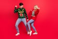 Photo of dreamy inspired couple dance have x-mas fun wear ugly sweater jeans shoes isolated red color background Royalty Free Stock Photo