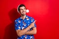 Photo of dreamy nice guy wear christmas hat print shirt look indicating at promo empty space isolated on vivid red color Royalty Free Stock Photo