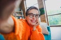 Photo of dreamy pretty elderly lady wear orange pullover spectacles arm hand cheek recording video indoors apartment Royalty Free Stock Photo