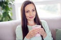 Photo of dreamy pretty mature lady wear teal pullover smiling sitting couch drinking coffee indoors house room Royalty Free Stock Photo