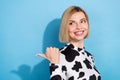 Photo of dreamy sweet woman dressed cow print outfit pointing thumb back looking empty space isolated blue color Royalty Free Stock Photo