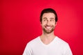 Photo of dreamy young positive man look empty space good mood cheerful isolated on red color background
