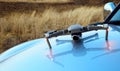 Photo of a drone with its reflection on the hood of a car and yellow autumn grass in the background