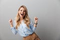 Photo of ecstatic blond businesswoman with long curly hair laughing and clenching her fists Royalty Free Stock Photo