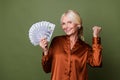 Photo of ecstatic woman with blond hair dressed silk shirt hold money win gambling clenching fist isolated on green Royalty Free Stock Photo