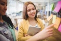 Photo editor with female coworker looking at sticky notes Royalty Free Stock Photo