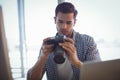 Photo editor holding camera while sitting in office