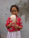 Photo editorial, 05 januari 2023, elementary school girl student eating cotton candy at indonesia