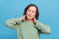 Photo of elder grey hair woman hands neck pain wear green jumper isolated on blue color background