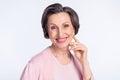 Photo of elderly attractive woman happy positive toothy smile hand touch cheek isolated over grey color background