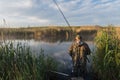 Photo of an elderly fisherman. A man in the early morning standing fishing on the shore of a small lake