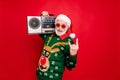Photo of elderly funny santa man holding vintage tape recorder at youngster party show horns wear sun specs x-mas ugly Royalty Free Stock Photo