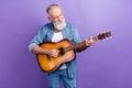 Photo of elderly handsome man happy positive smile play guitar concert isolated over purple color background
