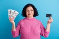 Photo of elderly woman happy positive smile hold cash money dollars credit card isolated over blue color background Royalty Free Stock Photo