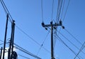 Electricity poles with lots of wires look running across against blue sky