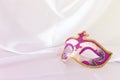 Photo of elegant and delicate pink, purple and gold venetian mask over white silk background. Royalty Free Stock Photo