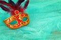 Photo of elegant and delicate red with gold Venetian mask over mint chiffon background