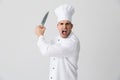 Agressive screaming young man chef indoors isolated over white wall background holding knife