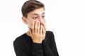 Photo emotional teenager, guy in black t-shirt, shows the emotions of fear, closing his mouth with his hands, on a white