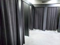 Image of empty fitting room in shopping mall with dark black curtains and mirrors