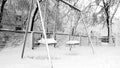 Closeup photo of empty snow covered playground after blizzard. Two swings under snow in the park