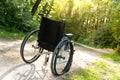 Empty wheelchair parked in park, health care concept with sun flare Royalty Free Stock Photo