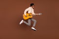 Photo of entertainer guy jump hold guitar play melody wear suspenders shoes isolated brown color background